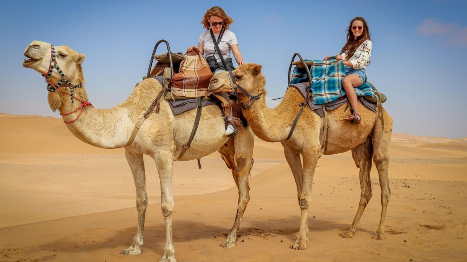 Two women on camels at the beach