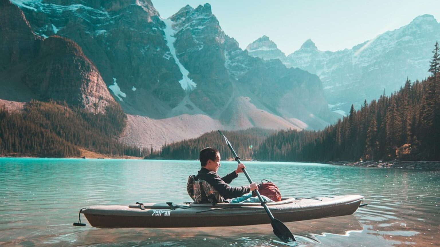 Man in a kayak with mountains behind
